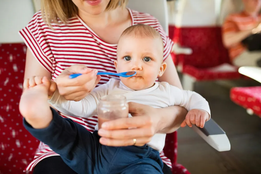 Miseczka z gładko zmiksowanym puree warzywnym (marchewka lub dynia) bez grudek, włókien ani skórek — obok łyżeczka do karmienia niemowlaka, neutralne jasne tło