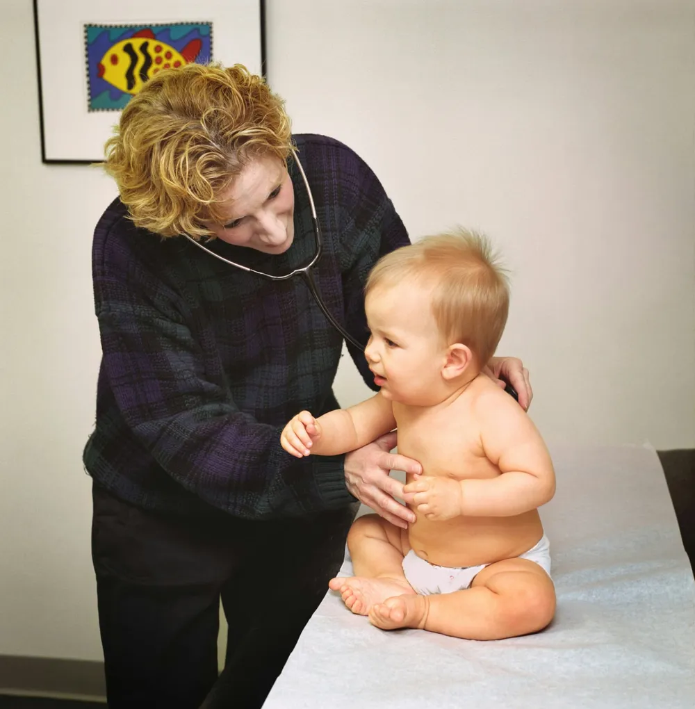 Rodzic z niemowlęciem na rękach rozmawia z pediatrą w gabinecie — konsultacja po wystąpieniu objawów alergii